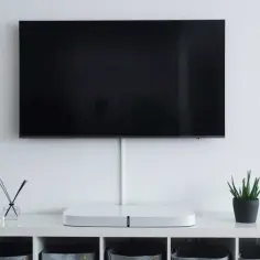 Minimalistyczny salon z telewizorem wiszącym na ścianie. Idealna wysokość, by wygodnie oglądać filmy, to klucz do komfortu.