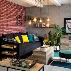 Nowoczesny salon z ceglaną ścianą, czarną kanapą i żółtymi poduszkami. Inspiracja, jak ozdobić ścianę w salonie, by nadać jej charakteru.