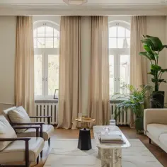 Elegancki salon z dwoma fotelami, sofą i marmurowym stolikiem. Inspiracja, jak urządzić salon: jasne zasłony, dużo zieleni i stylowe dodatki.