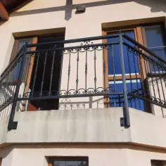 Solidne mocowania balustrady balkonowej z kutego żelaza, ozdobione misternymi wzorami, zapewniają bezpieczeństwo i elegancję.