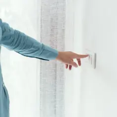 Dłoń naciska włącznik światła, pokazując, jak podłączyć oświetlenie.