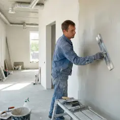 Tynkarz wygładza ścianę. Czas schnięcia tynków cementowo wapiennych zależy od warunków.