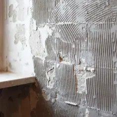 Ściana z resztkami kleju po płytkach i fragmentem parapetu okiennego.