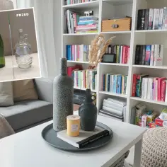 Inspiracja na to, jak zrobić tynk dekoracyjny samemu, z butelkami i książkami na stoliku.
