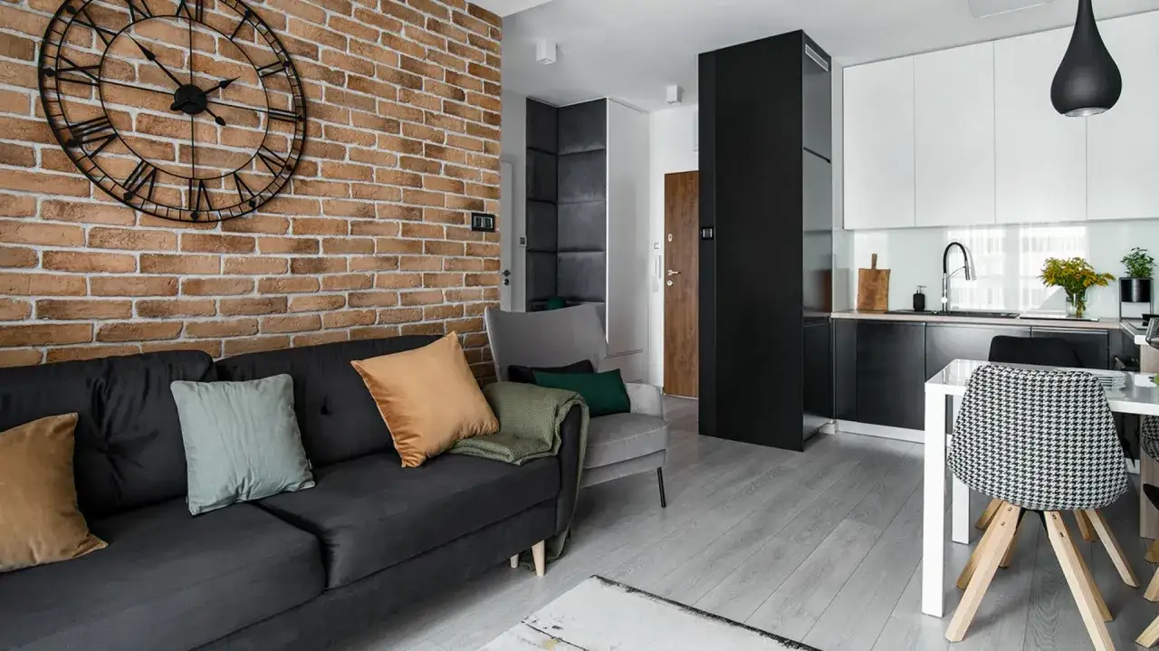 Nowoczesny salon z ceglaną ścianą i dużym zegarem – inspiracja, jak ozdobić ścianę w salonie.