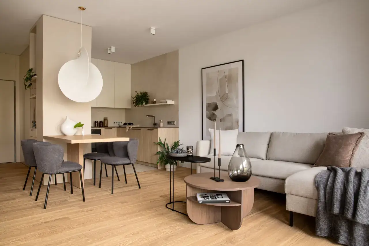 Nowoczesny salon z aneksem kuchennym. Jasne kolory, drewniana podłoga i minimalistyczne meble tworzą przytulną atmosferę. Inspiracja, jak urządzić salon.
