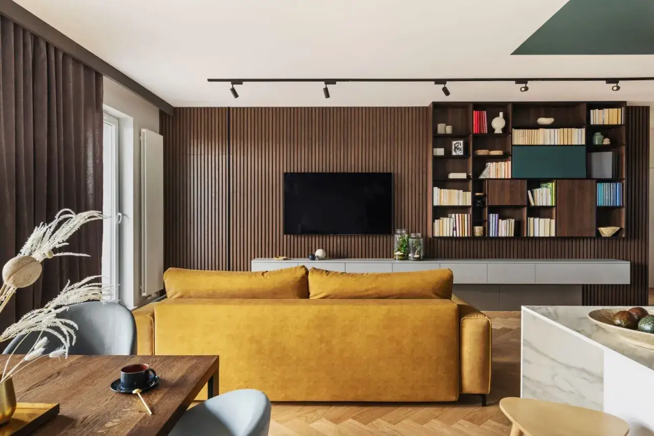 Nowoczesny salon z żółtą kanapą i drewnianą zabudową. Inspiracja, jak urządzić salon, by był przytulny i stylowy.