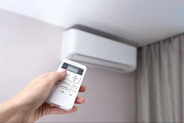 Dłoń trzymająca pilot do klimatyzatora, gotowa do rozpoczęcia montażu klimatyzatora krok po kroku.
