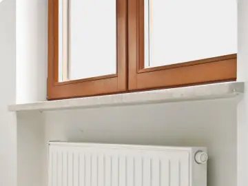 Drewniane okno, kamienny parapet i biały grzejnik. Idealne miejsce, by zastanowić się, kiedy montować parapety wewnętrzne.